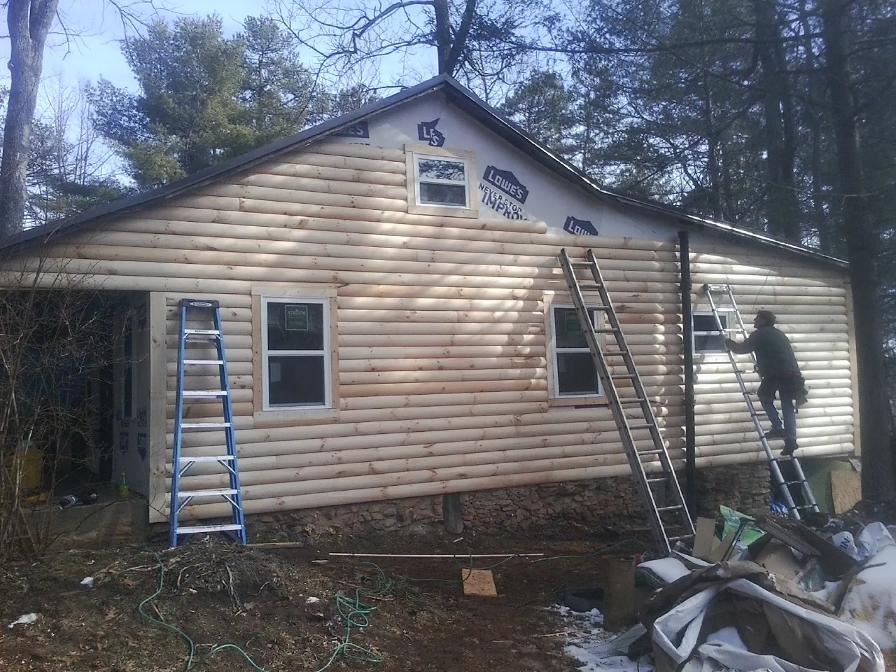 Ladders set against fresh log siding during an exterior remodel in Rock Port