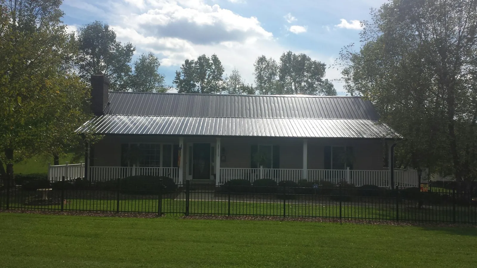 Gray metal roof on a brick ranch with a full width front porch — Gutter Guard Installation work by our crew in Rock Port