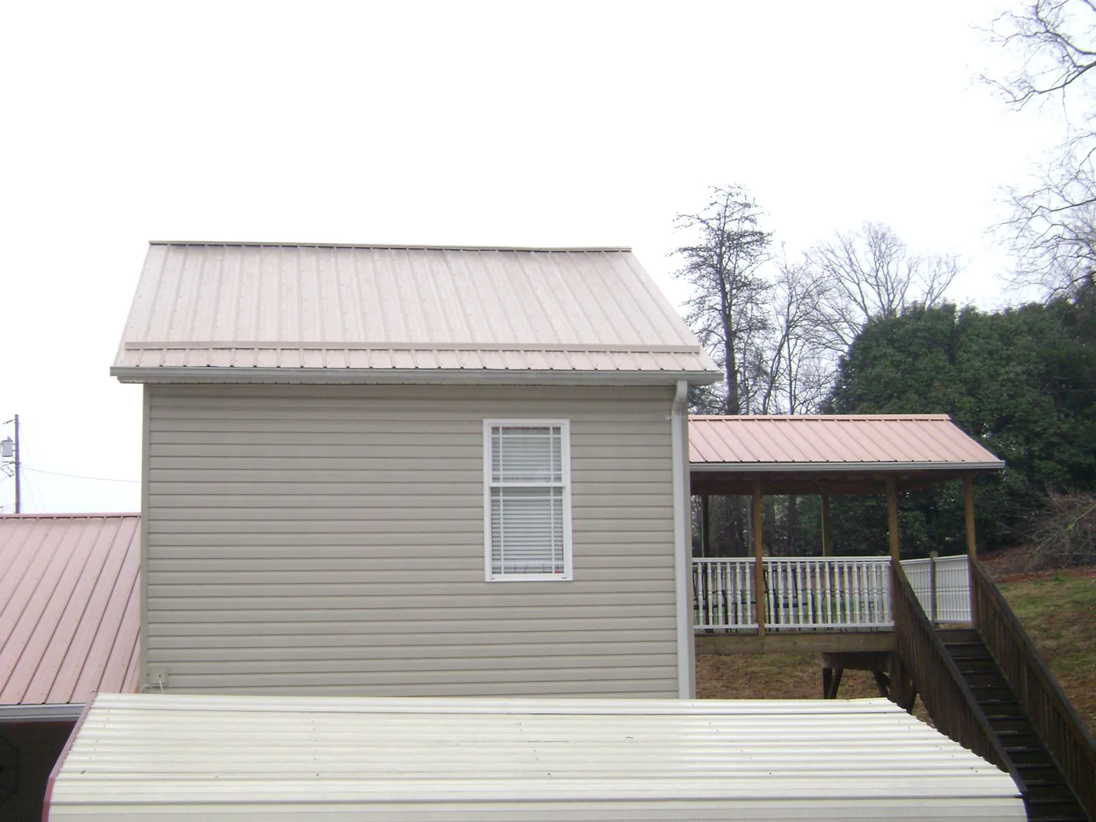 Tan metal roofs on a two story addition and attached porch, from a Roof Replacement job in Rock Port