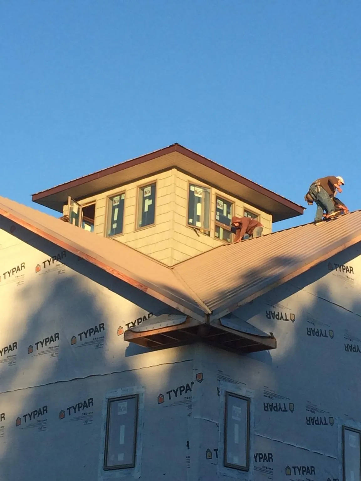 Roofers working around a rooftop cupola on a new metal roof at sunset — Roof Waterproofing in Rock Port by Roofing Brothers